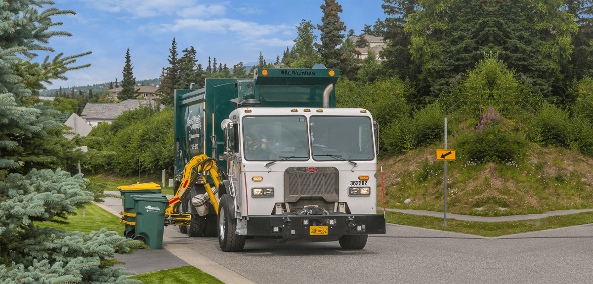 Photo of Alaska Waste truck servicing trash and recycling carts in a residential area.